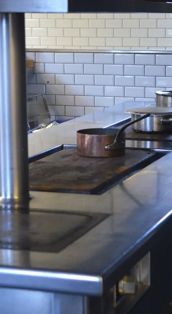 Stainless-steel work surfaces and equipment in an empty commercial kitchen.