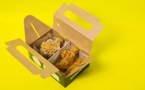 Open cardboard takeaway food box on a bright yellow surface.